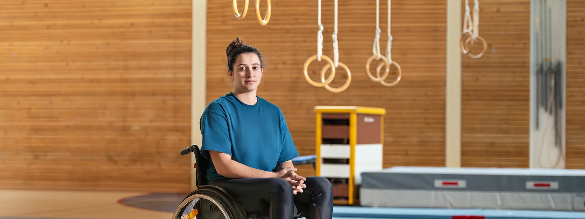 Giulia Damiano est assise dans son fauteuil roulant dans une salle de gymnastique.